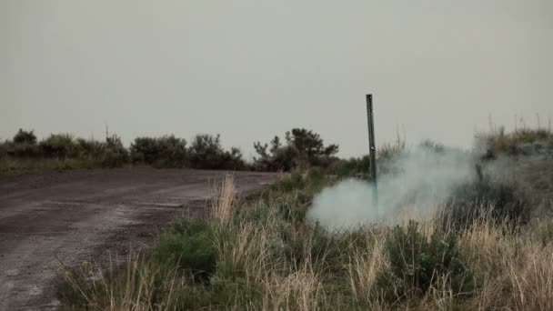 Un explosif d'entraînement près d'un poteau dégage de la fumée, puis explose 