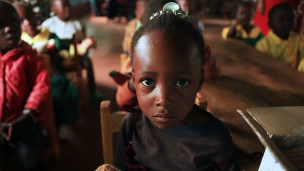 Lindos niños africanos se sientan en pequeñas mesas en un edificio escolar de Kenia, África — Vídeos de Stock