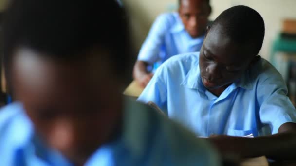 School jongen lezen van een boek in de klas dan kijken naar de camera in Kenia. — Stockvideo