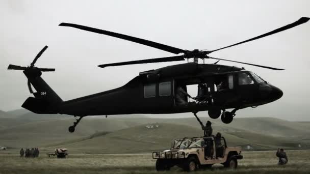 Helicopter attaching and hauling off Humvee from field — Stock Video