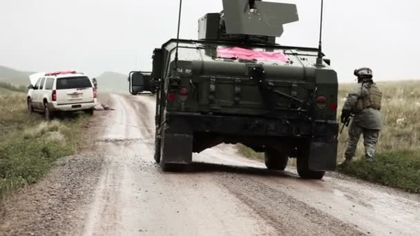 Żołnierz w pobliżu Humvee na błotnistej drodze, z ogniem pistoletu — Wideo stockowe