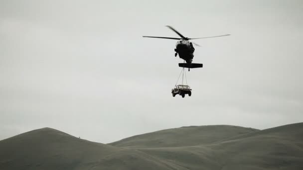 Helicopter bringing a Humvee down to land — Stock Video