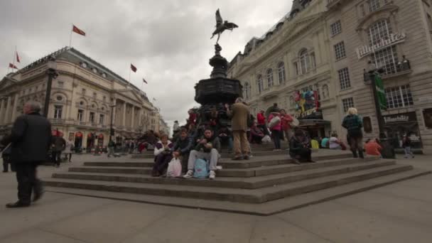 İnsanlar Londra'daki Eros heykelinin merdivenlerinde sitts — Stok video