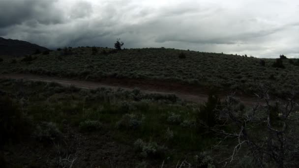 Mirada de lapso de tiempo de nubes que pasan sobre una colina arbustiva con un camino de tierra . — Vídeo de stock