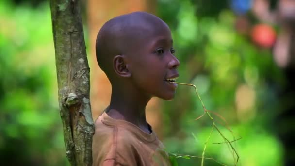 Um jovem menino africano canta enquanto se inclina contra um broto no Quênia, África — Vídeo de Stock