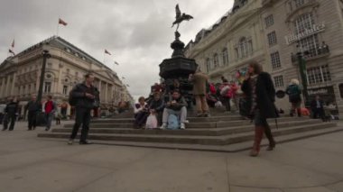 İnsanlar Londra'daki Eros heykelinin merdivenlerinde yemek yiyor.