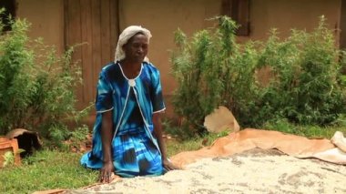 Bir kadın battaniyenin yanında diz çöker ve Kenya, Afrika'da üzerine bir şeyler serpişdiriyor.