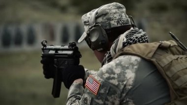 Kulak korumalı asker kısa patlamalarla mp5 vuruyor