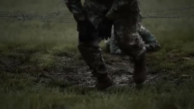 Düşük dikenli tel altında sürünerek askerler 