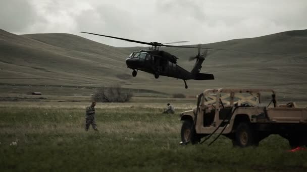 Helicóptero aterrizando en el campo con Humvee y soldados circundantes — Vídeos de Stock