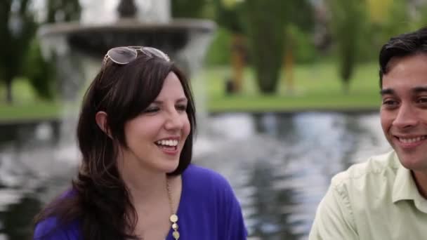 Nahaufnahme eines jungen Paares, das vor einem Wasserbrunnen miteinander flirtet. — Stockvideo