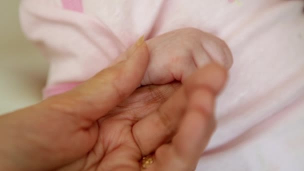 Een close-up shot van een oudere vrouw die de hand van een baby vasthoudt. — Stockvideo