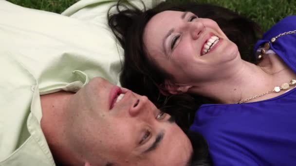 A close up shot of a couple laying on the green grass next to each other. — Stock Video