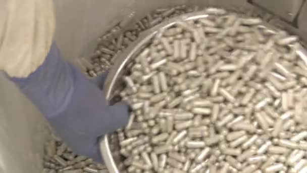 Closeup pan of a gloved hand scooping capsules. — Stock Video