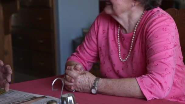 Ένα σφηνάκι από ένα ηλικιωμένο ζευγάρι που μιλάει μεταξύ τους στο τραπέζι σε ένα δωμάτιο με μπλε τοίχους. — Αρχείο Βίντεο