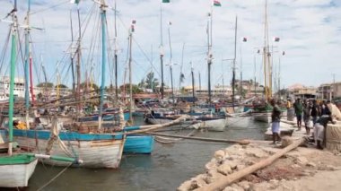 Kıyıda duran erkeklerle dayalı yelkenli tekneler.