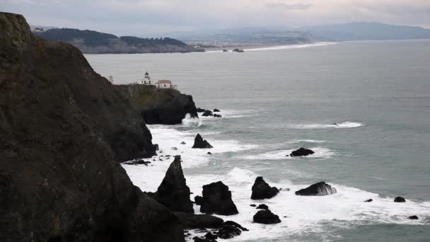 Rochas irregulares e farol com as ondas batendo . — Vídeo de Stock