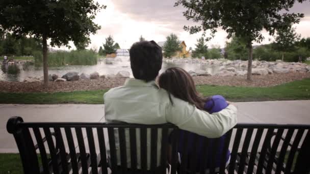 Un coup de pistage du dos d'un couple assis sur un banc regardant au loin . — Video