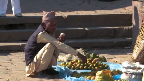 Nepali Mann hockt und isst auf einem Markt. — Stockvideo