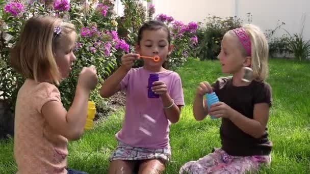 Küçük kızlar baloncuklar bir bahçede üfleme — Stok video