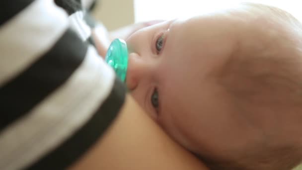 Um tiro de perto de um jovem balançando um lindo bebê em seus braços . — Vídeo de Stock