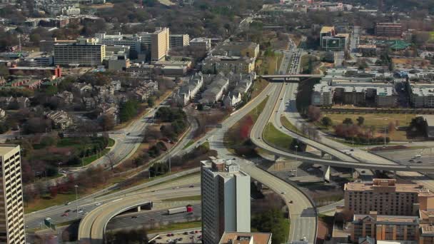 Automobili che scorrono sulla superstrada sotto i ponti con edifici che li circondano . — Video Stock