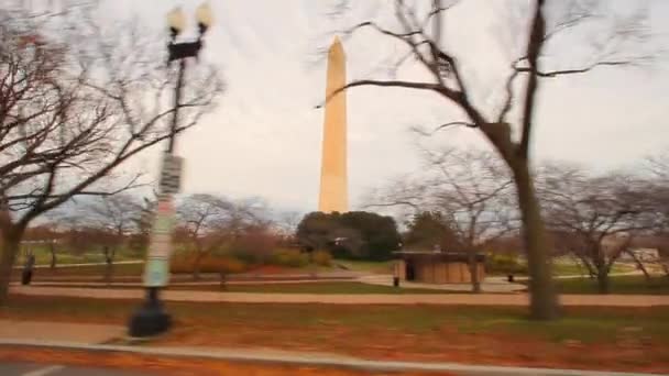 Медленная съемка монумента Вашингтона с деревьями на переднем плане . — стоковое видео