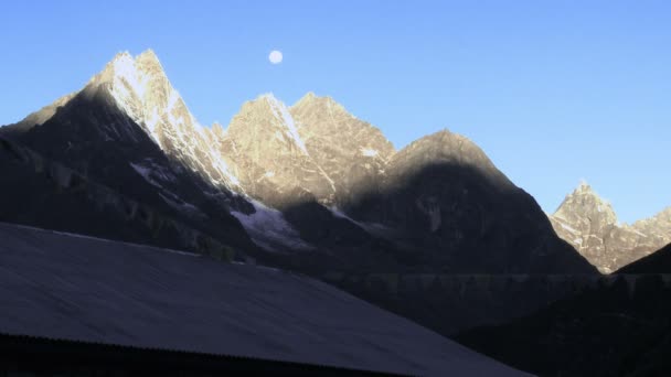 Prayer flags waving below morning sunlit Himalayan peaks. — Stock Video