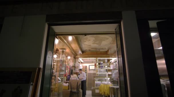 Tilting down shot from outside looking in on an Italian cafe. — Stockvideo