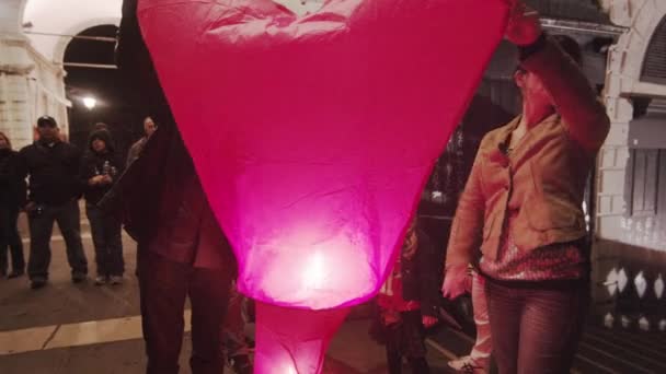 Twee mensen houden een verlichte, hear-vormige papier Lanter — Stockvideo