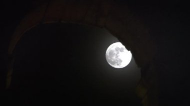 full moon hiding behind Colosseum
