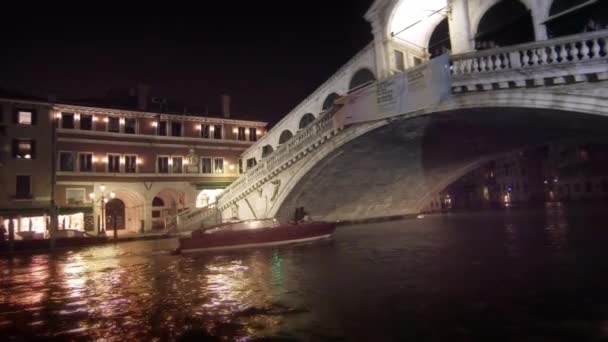 A single motor boat travels underneath the Rialto Bridge — Stockvideo
