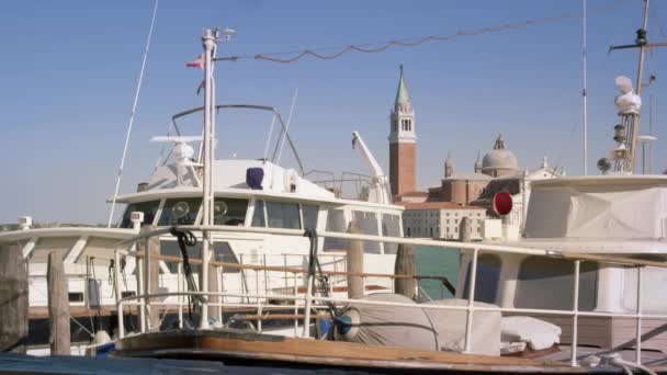 Static shot of a boat docked at a marina with the Island of San Giorgio in the background. — Stock Video