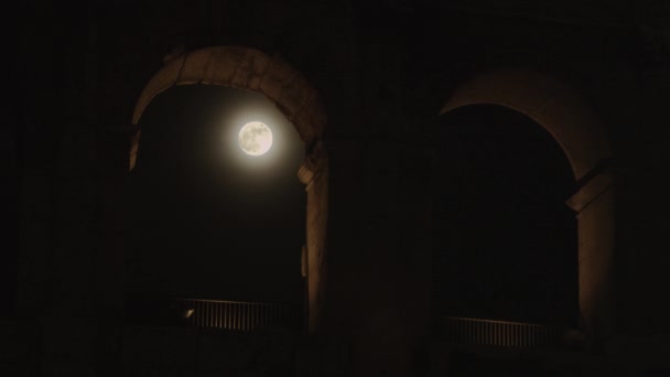 Full moon genom bågen av Colosseum på natten — Stockvideo