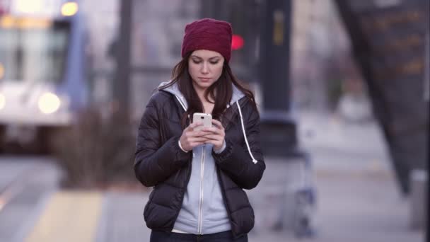 Nahaufnahme einer Frau, die auf dem Gehweg steht und auf ihr Smartphone schaut. — Stockvideo