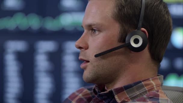 Hombre hablando en auriculares delante de la pantalla del ordenador — Vídeos de Stock