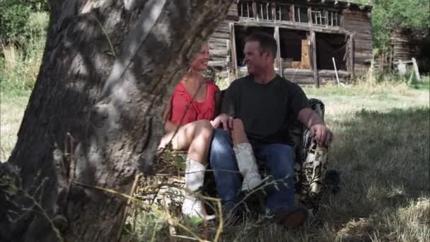 Στοργικό ζευγάρι που κάθεται σε έναν καναπέ σε εξωτερικούς χώρους σε ένα αγρόκτημα — Αρχείο Βίντεο