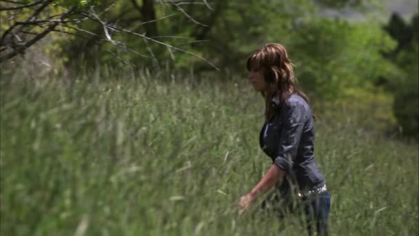 Slow motion shot of a young woman sitting down in tall grass. — Stock Video