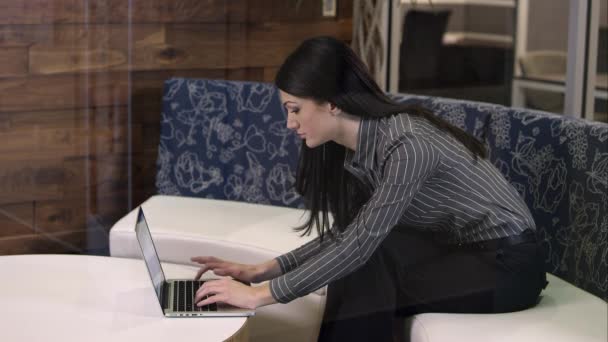 Woman leaning over to type on laptop. — Stock Video