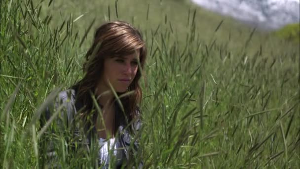 Slow motion skott av en ung kvinna som sitter ner i högt gräs. — Stockvideo