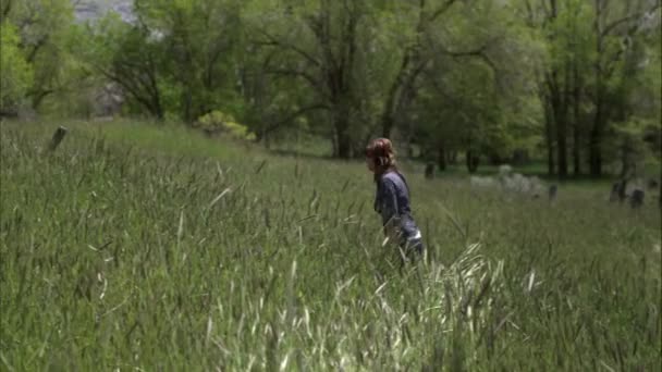 Fotografía en cámara lenta de una mujer caminando a través de hierba alta . — Vídeos de Stock