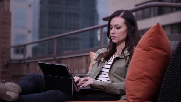 Mulher relaxante no topo do telhado digitação no laptop correndo dedos através do cabelo . — Vídeo de Stock