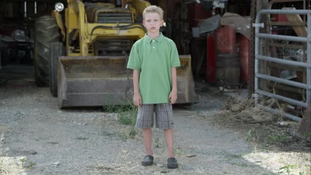 Niño con labio leporino parado delante del tractor . — Vídeos de Stock