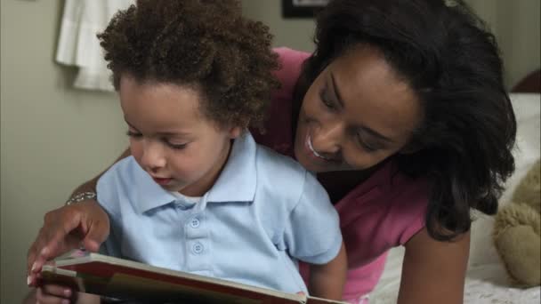 Slow motion av mor pussar pojke läser bok. — Stockvideo
