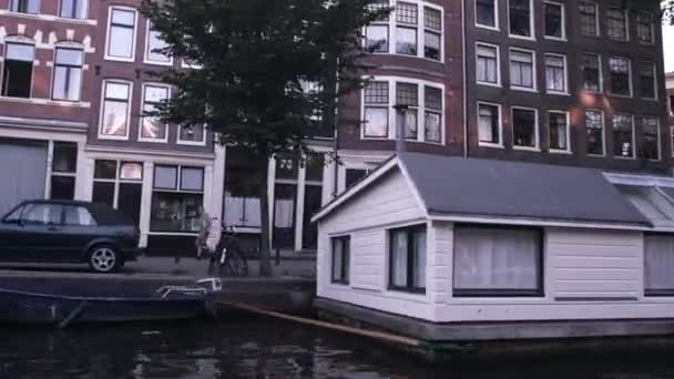 Opptrappingsvideo av bygninger på gate og husbåter langs kanalen i Amsterdam – stockvideo
