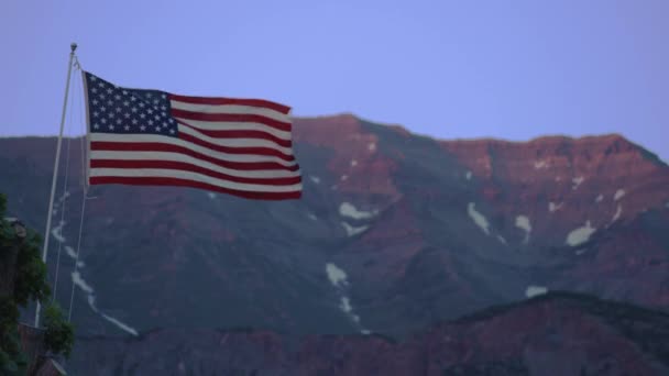 Bandera americana ondeando frente a una montaña — Vídeos de Stock