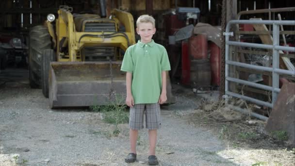 Мальчик с расщелиной губы, улыбающийся перед трактором . — стоковое видео
