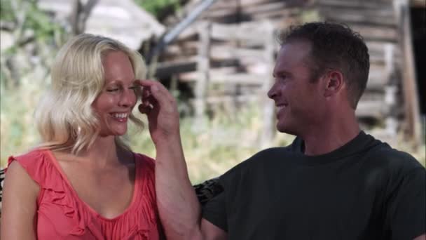 Langzame tracking shot van een paar lacht en aanraken terwijl buitenshuis op een boerderij — Stockvideo