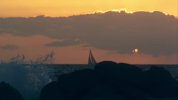 Golven op de rotsen bij zonsondergang — Stockvideo