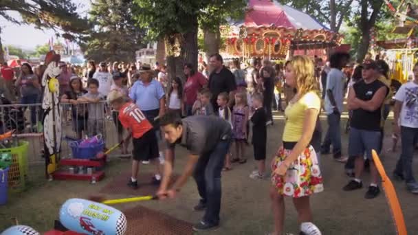 Uomo e ragazza che fanno un gioco di martello a un carnevale — Video Stock